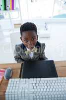 High angle view of boy imitating as businessman sitting in office
