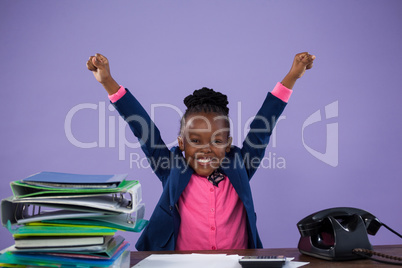 Portrait of happy businesswoman with arms raised at desk