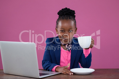 Portrait of businesswoman having coffee while making face