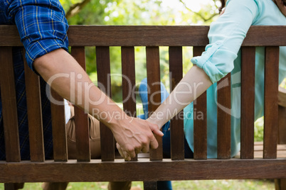 Couple sitting on bench and holding hand in garden