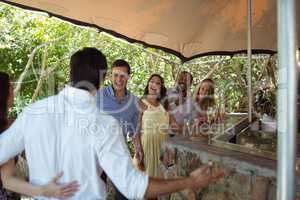 Smiling friends interacting while having a champagne at counter