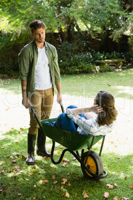 Man interacting with woman while pushing wheelbarrow in garden