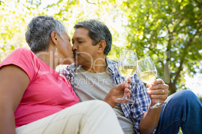 Senior couple kissing while drinking wine