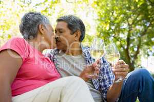 Senior couple kissing while drinking wine