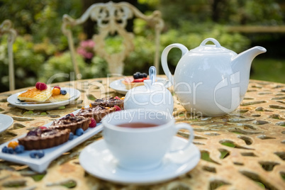 Cup of tea with dessert and teapot on table