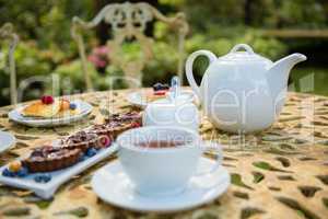 Cup of tea with dessert and teapot on table