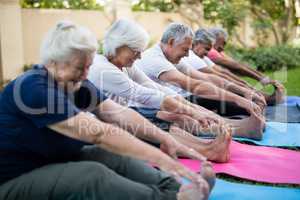 Smiling multi-ethnic senior people doing stretching exercise