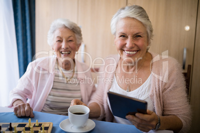 Portrait of smiling senior friends having coffee while playing chess