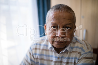 Portrait of serious senior man by window