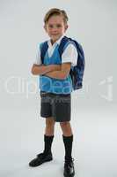 Portrait of cute schoolboy standing with arms crossed