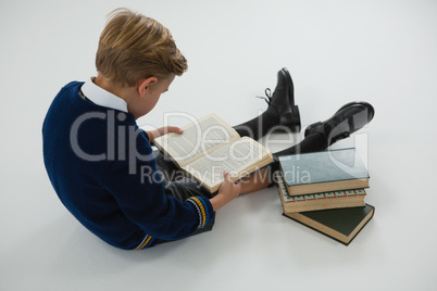 Schoolboy reading book on white background