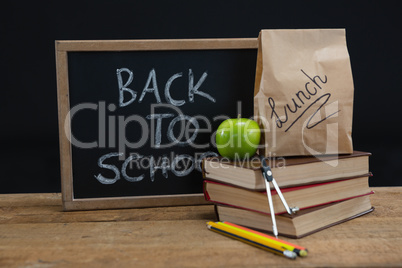 Lunch paper bag, green apple and slate with text back to school on wooden table