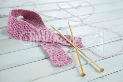 Close-up of woolen Breast Cancer Awareness ribbon with needles and heart shape