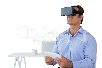 Businessman holding tablet while wearing vr glasses