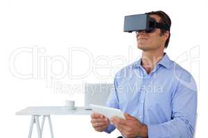 Businessman holding tablet while wearing vr glasses