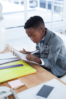 Businessman writing on paper attached to clipboard