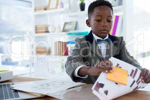Serious businessman reading documents while sitting at desk