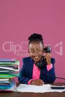 Portrait of smiling businesswoman talking on telephone while doing paperwork