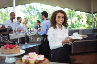 Waitress holding coffee tray in outdoor cafe