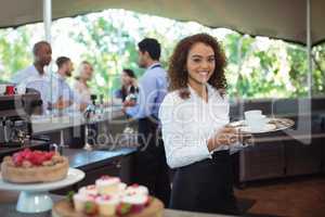 Waitress holding coffee tray in outdoor cafe