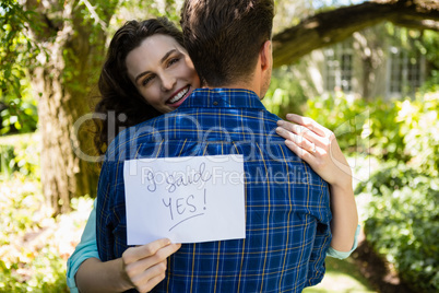 Couple holding I sad yes paper while embracing each other
