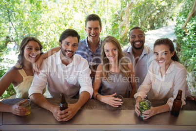 Portrait of smiling friends having alcohol at counter