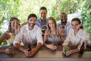 Portrait of smiling friends having alcohol at counter