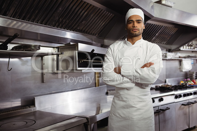 Portrait of confident chef standing with arms crossed in commercial kitchen