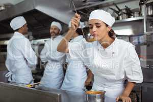 Chef tasting food from spoon in kitchen