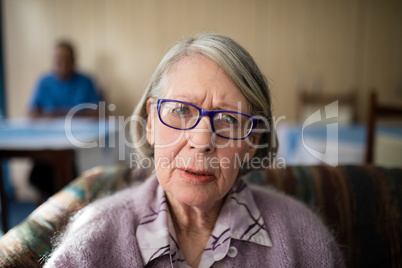 Portrait of worried senior woman sitting on armchair