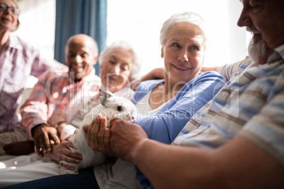 Senior woman holding rabbit while sitting with friends