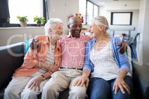 Smiling senior man sitting with arm around over females