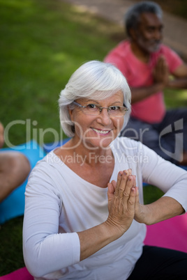 High angle view of smiling senior woman meditating in prayer position