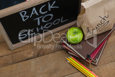 Lunch paper bag, green apple and slate with text back to school on wooden table