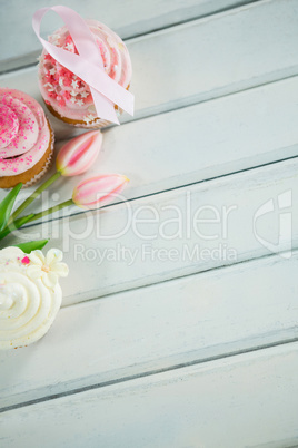 Overhead view of Breast Cancer Awareness pink ribbons on cupcakes with tulips
