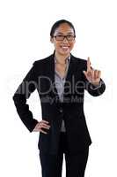 Smiling businesswoman with hand on hip touching invisible interface