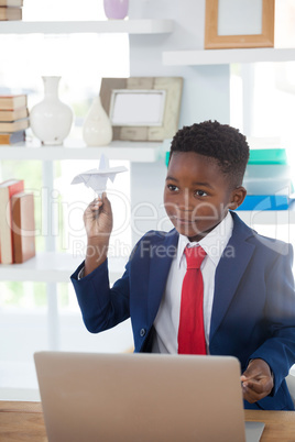 Boy imitating as businessman playing with paper airplane