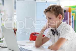 Concentrated businessman working on laptop while sitting at desk