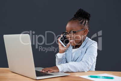 Smiling businessman using mobile phone while working on laptop