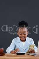 Happy businesswoman calculating paper currency at desk