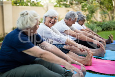 Smiling senior woman with friends exercising on mats