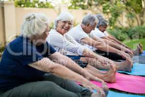 Smiling senior woman with friends exercising on mats