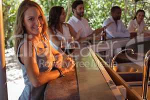 Portrait of smiling woman having a glass of red wine at counter