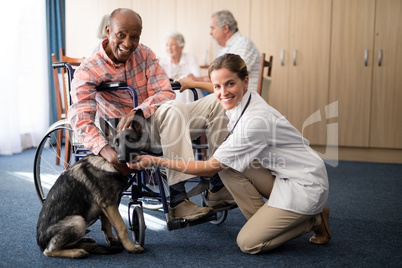 Portrait of smiling female doctor kneeling by disabled senior man stroking puppy