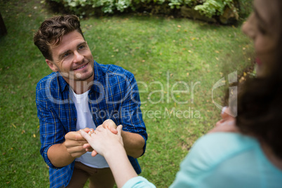 Handsome man wearing engagement ring to woman