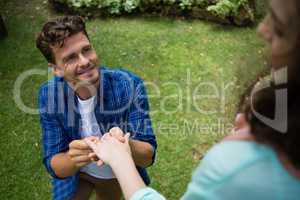 Handsome man wearing engagement ring to woman