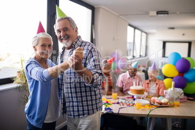 Portrait of smiling senior couple holding hands at party
