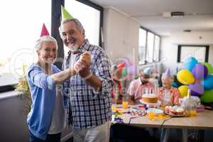 Portrait of smiling senior couple holding hands at party