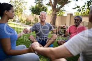 Smiling senior people meditating with young trainer