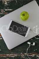 Mobile phone and green apple on laptop